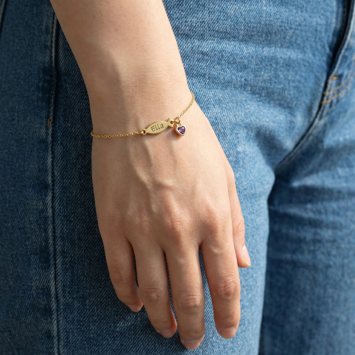 Ichthys Armband mit Geburtsstein – Frau trägt goldenes Armband mit Fisch-Anhänger am Handgelenk