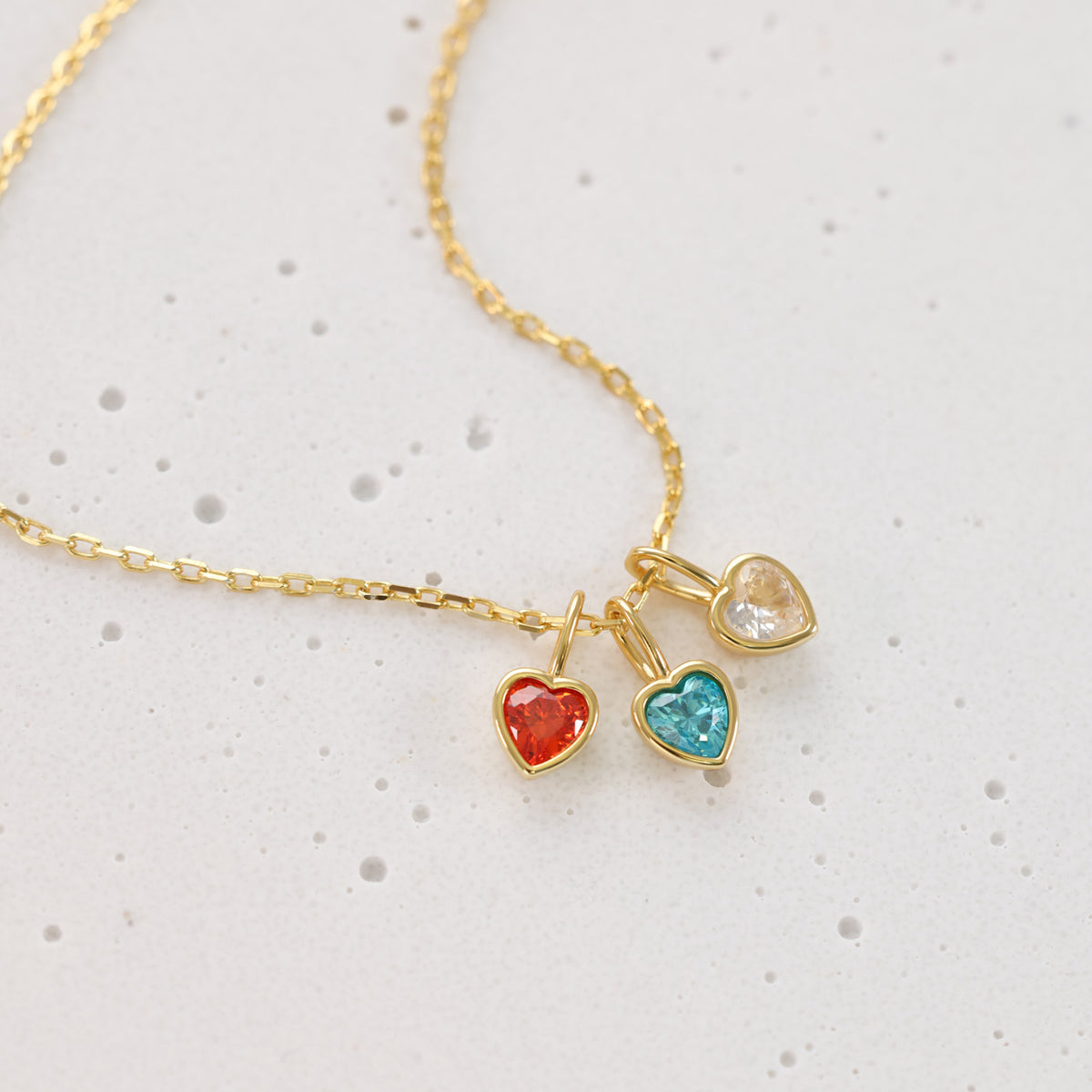 Goldene Kette mit drei herzförmigen Geburtsstein-Anhängern in Rot, Türkis und Champagner