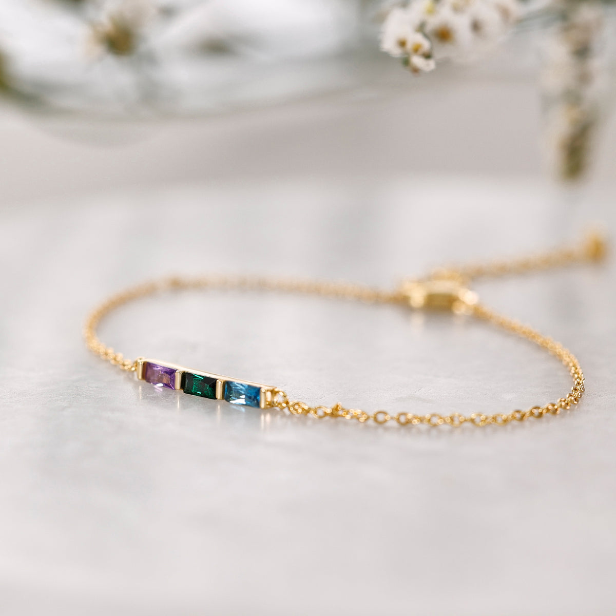 Personalisiertes Geburtsstein-Armband in Gold mit drei Baguette-Steinen in Nahaufnahme