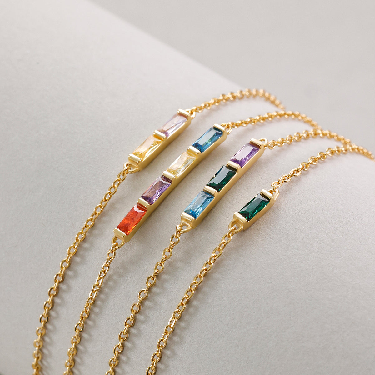 Personalisiertes Geburtsstein-Armband in Gold mit vier bunten Baguette-Steinen als Variantenübersicht