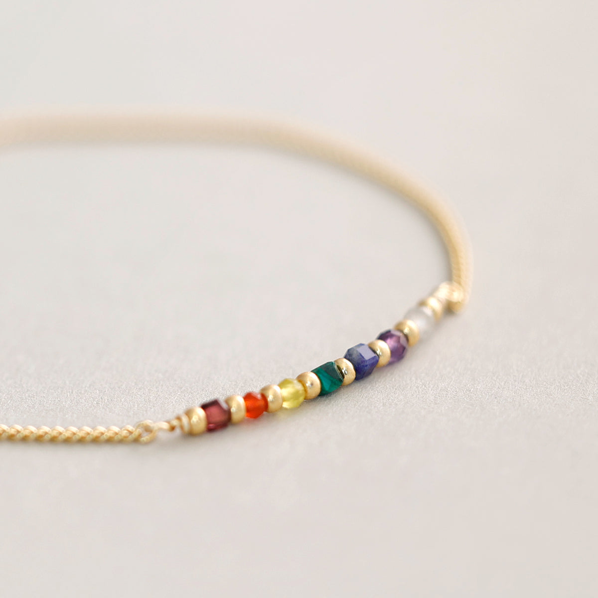 Chakra Armband in Gold, Makroaufnahme der Edelstein-Perlen in Regenbogenfarben