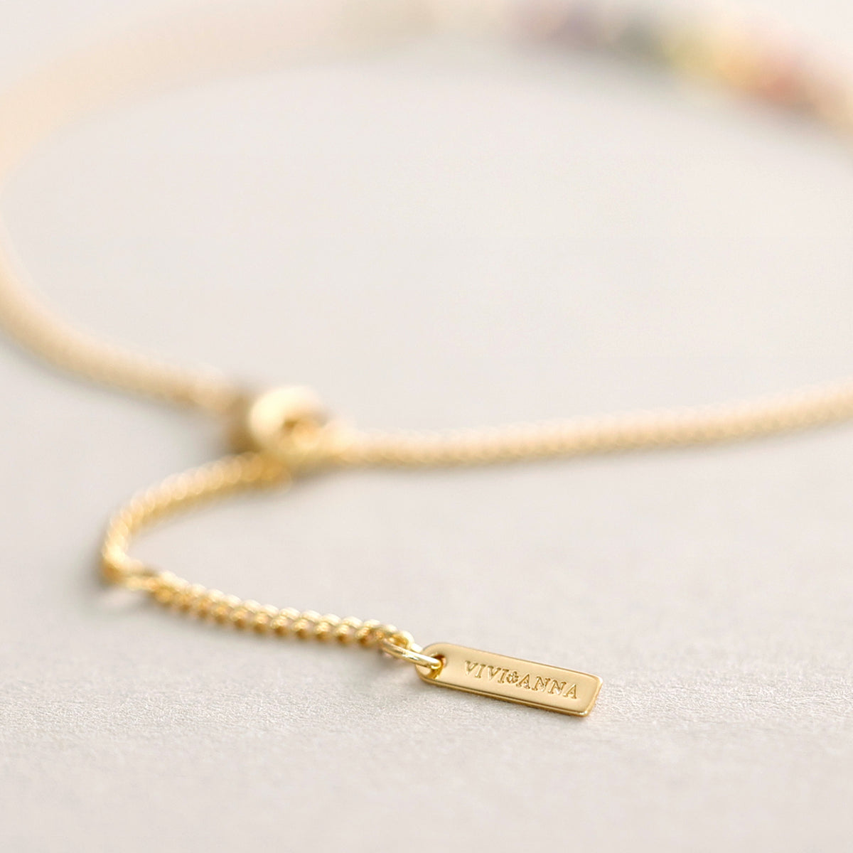 Chakra Armband in Gold, Nahaufnahme der bunten Chakra-Perlen mit VIVI&ANNA-Anhänger