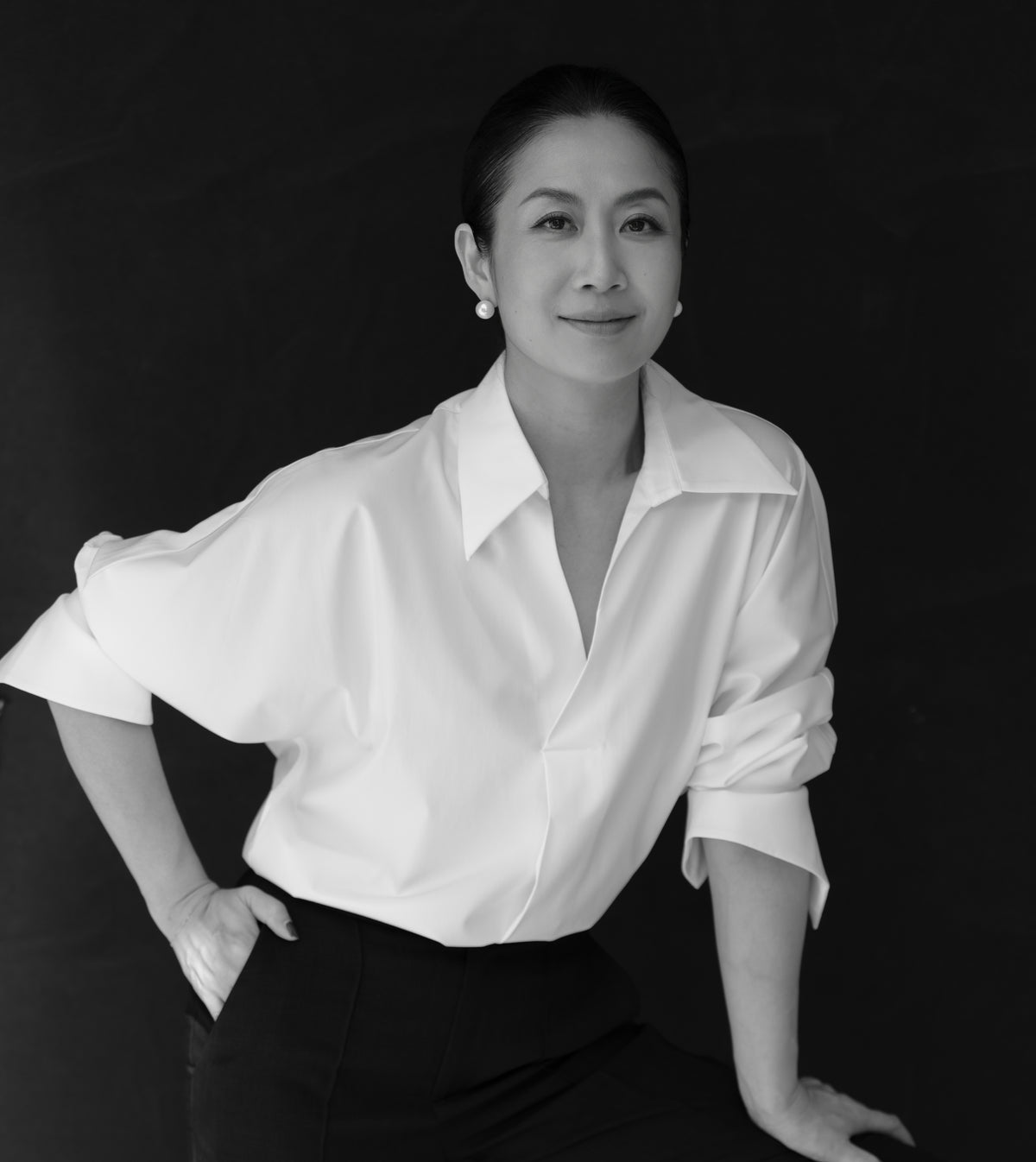 Schwarzweiß-Porträt der Gründerin in weißer Bluse vor dunklem Hintergrund