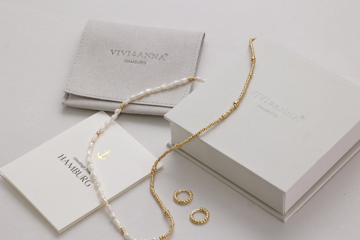 Fertig verpacktes Geschenk: Schmuckbeutel, Karte, Perlen-Gold-Kette und kleine Creolen