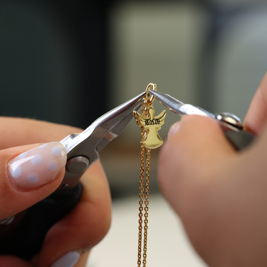 Goldener Schutzengel-Anhänger mit Datumsgravur wird mit der Zange an die Kette gesetzt
