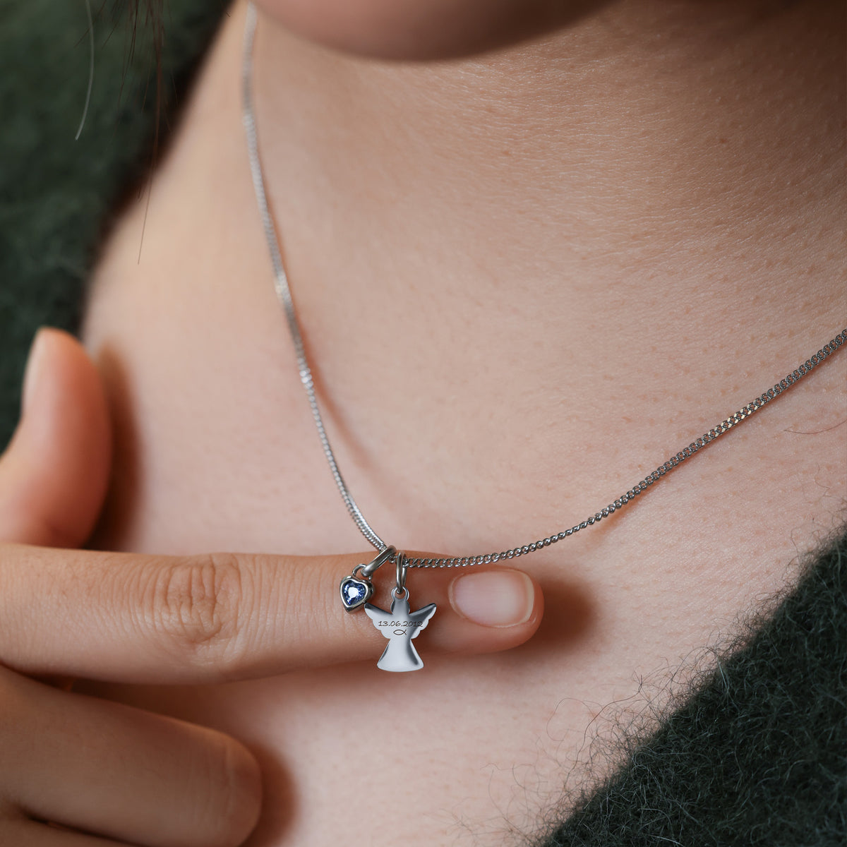 Frau trägt Schutzengel-Kette mit Herz Geburtsstein in Silber mit blauem Stein