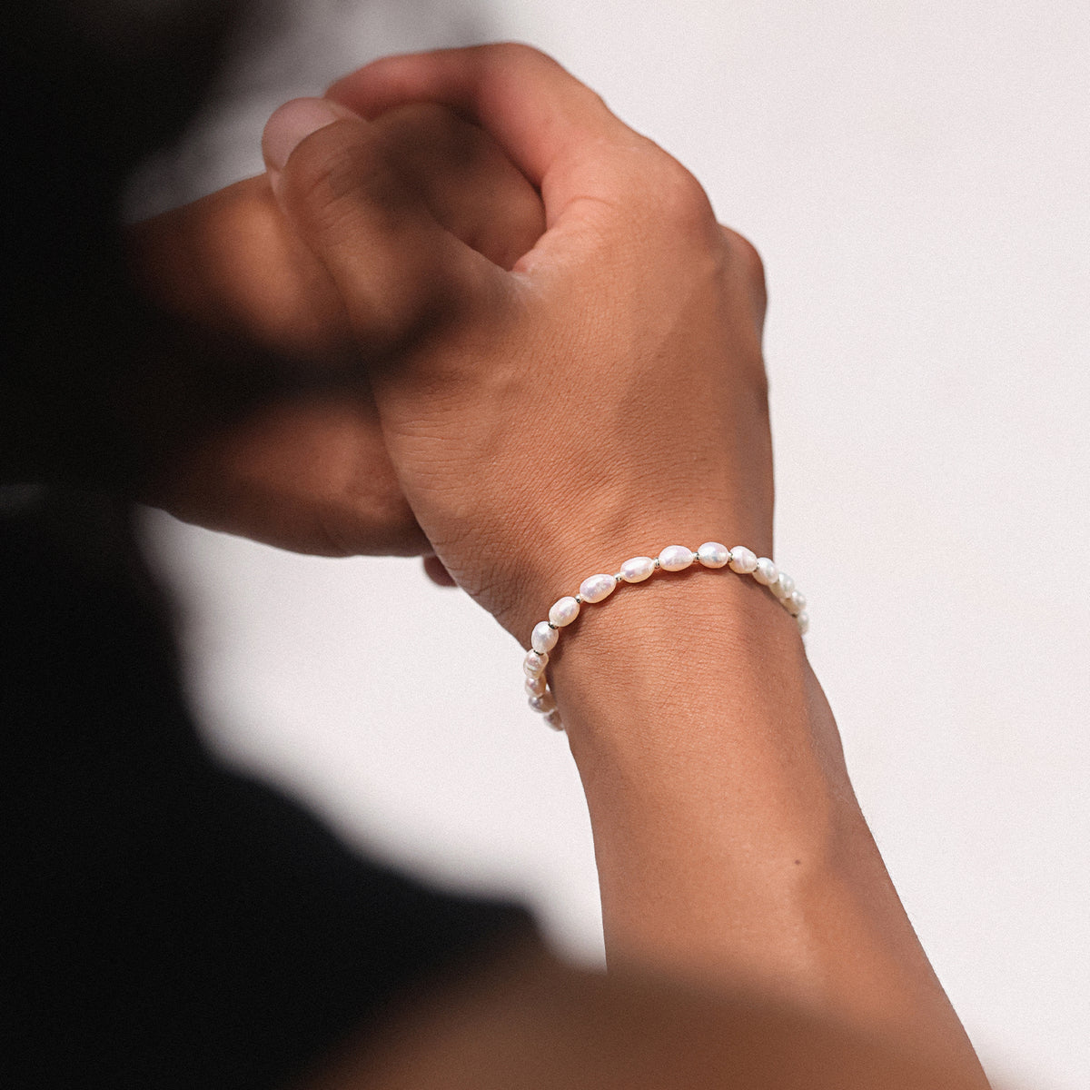 Zwei Personen halten Hände, eine trägt das Süßwasserperlenarmband