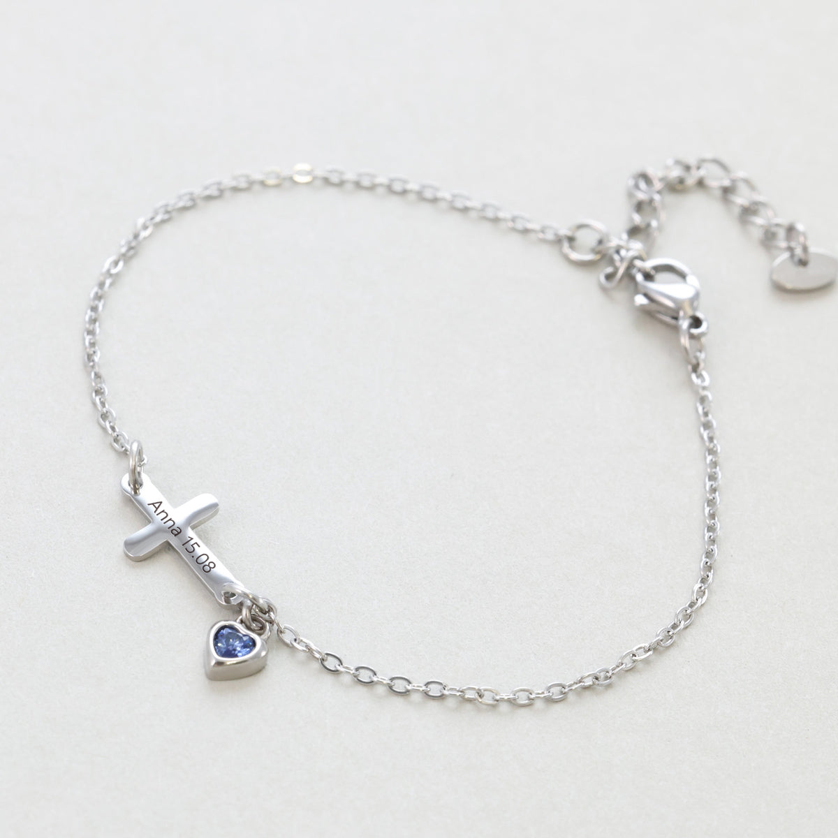 Kreuzarmband mit Herz-Geburtsstein – silbernes Armband graviert 'Anna 15.08' mit blauem Herzstein