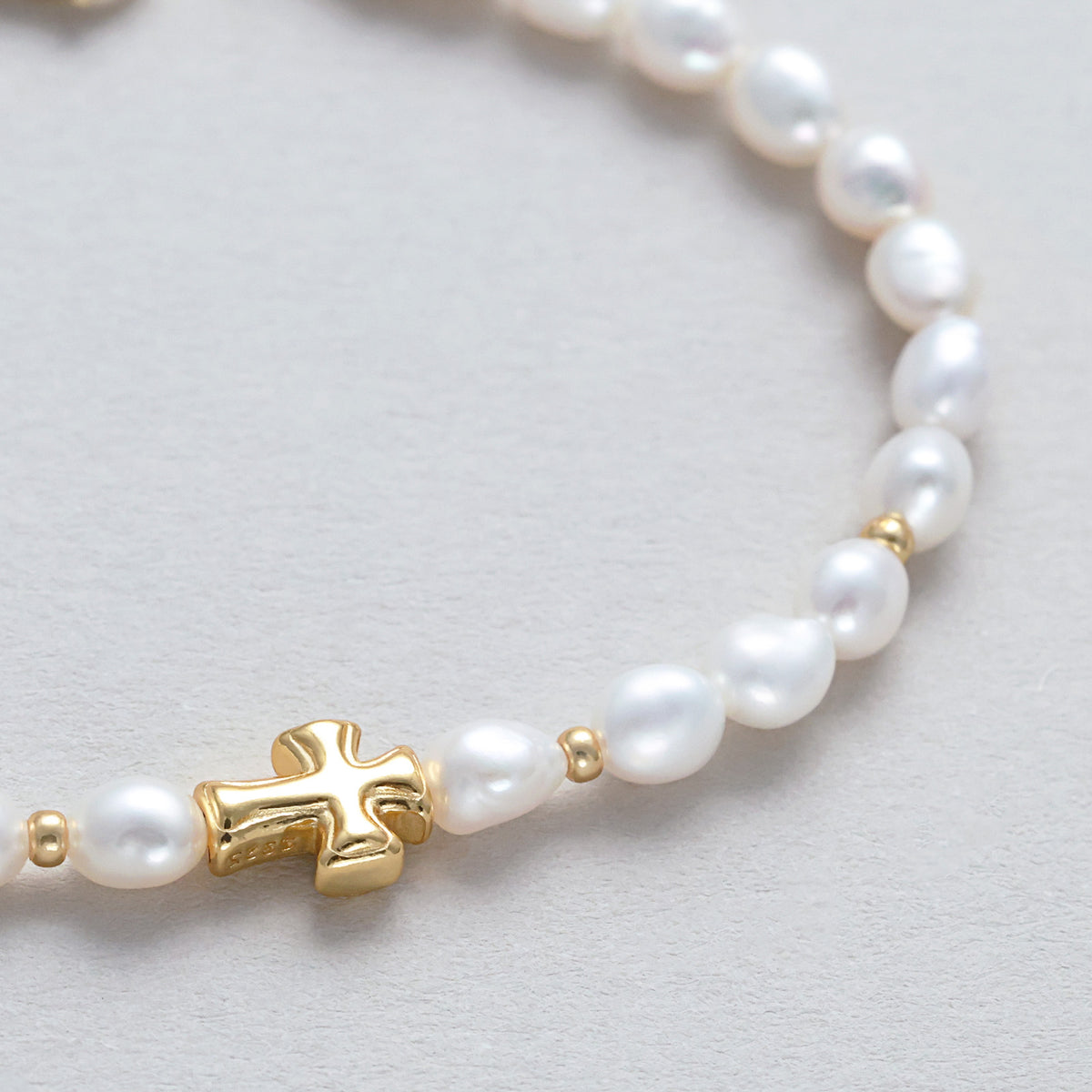 Süßwasserperlen Armband mit zartem Kreuz – Nahaufnahme des goldenen Kreuzanhängers zwischen den Perlen