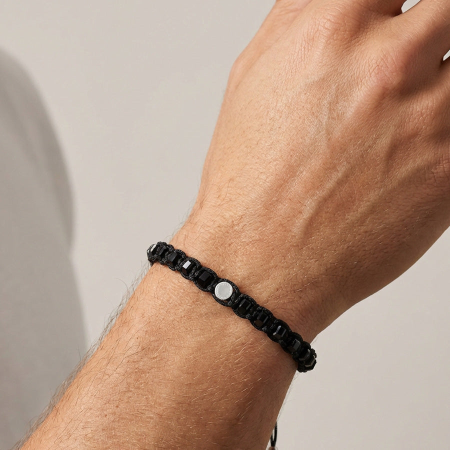 Person trägt schwarzes Onyx Armband mit runder Silberplakette am Handgelenk, Nahaufnahme