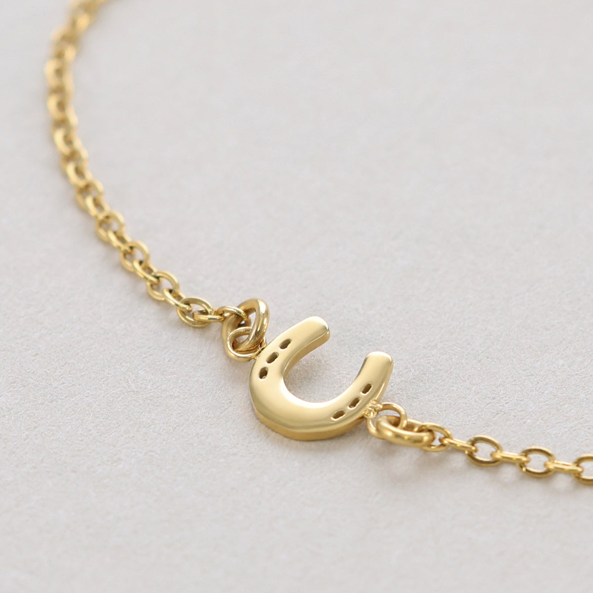 Glücksbringer Armband mit Hufeisen – Nahaufnahme des goldenen Hufeisen-Anhängers an der Kette