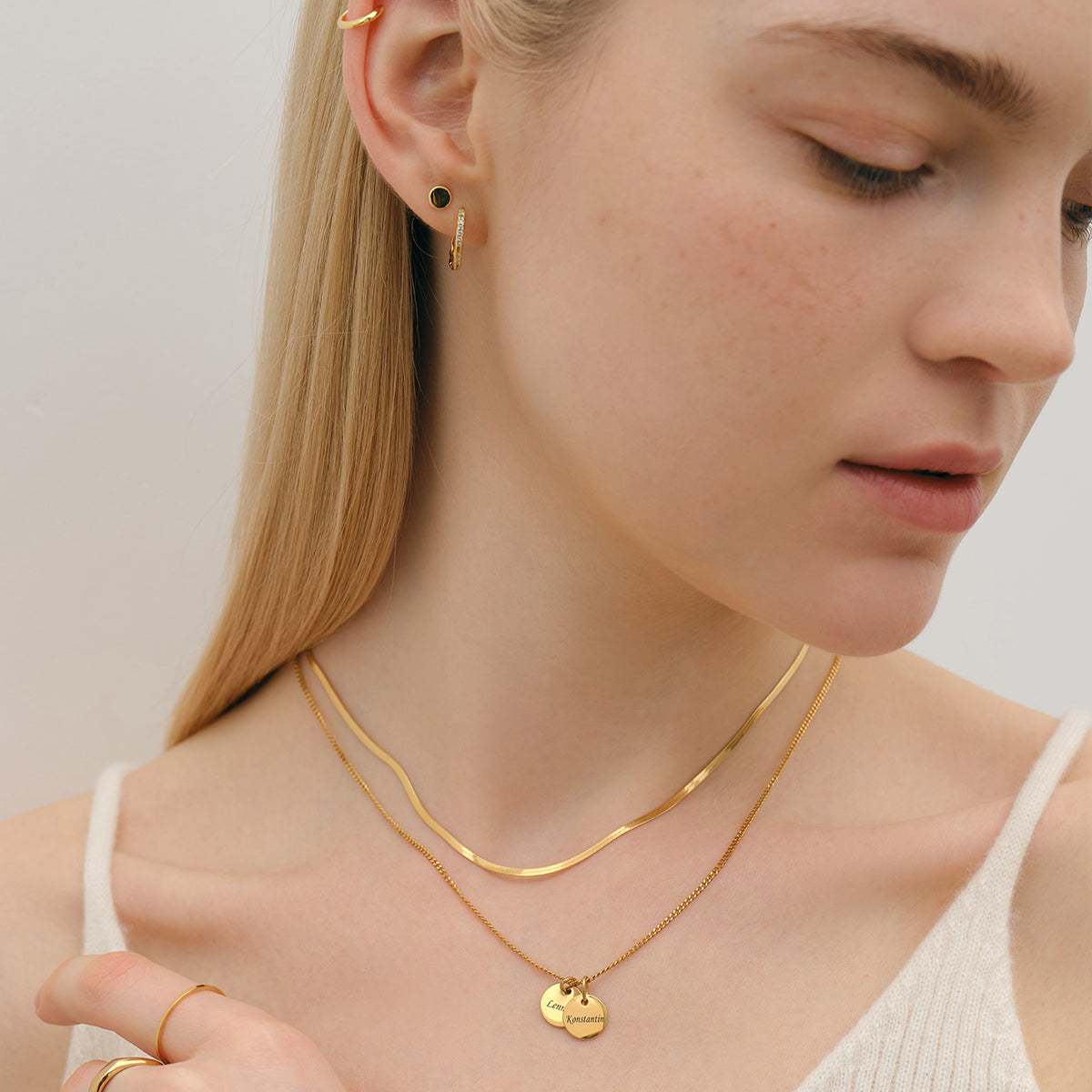 Personalisierte Kette mit rundem Plättchen – Frau trägt goldene Kette mit Anhänger, Nahaufnahme an Ohr und Hals