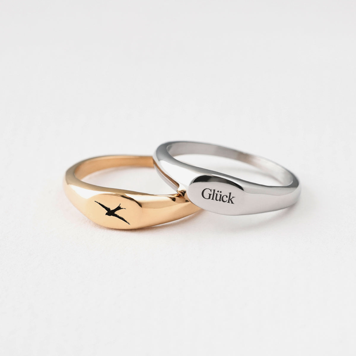 Mini-Siegelring mit Gravur in Gold mit Vogelmotiv und in Silber mit Schriftzug Glück