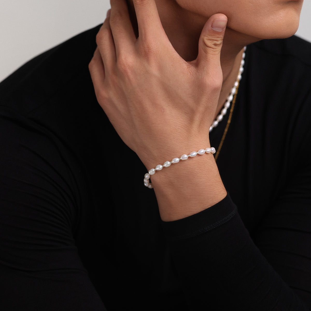 Person trägt Süßwasserperlenarmband am Handgelenk, dazu eine goldene Halskette