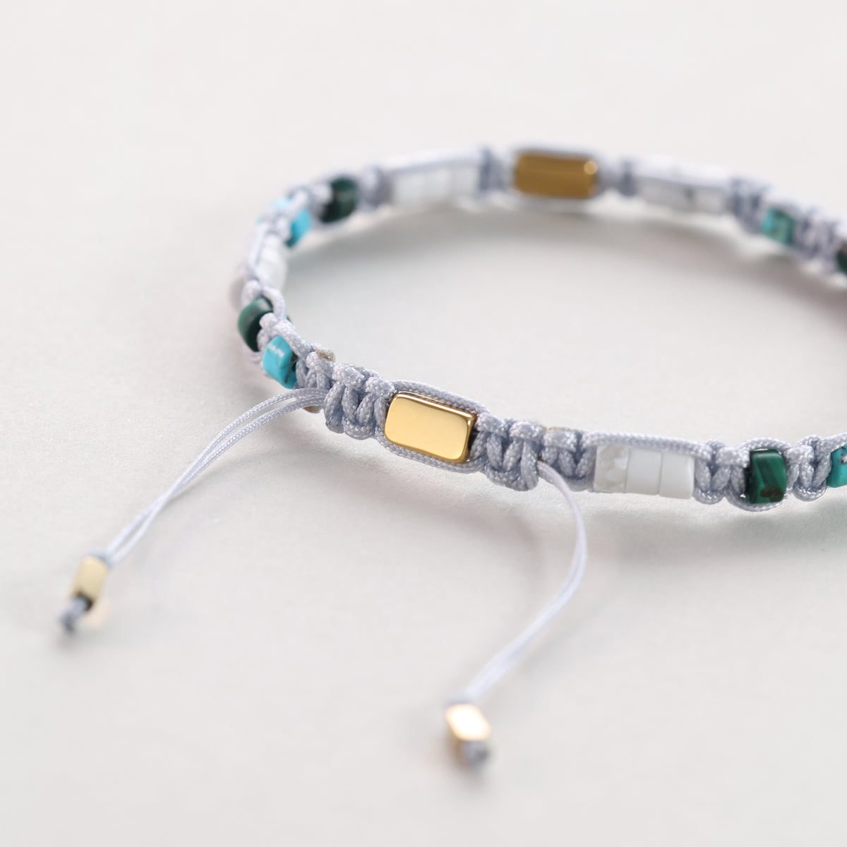 Nahaufnahme der goldenen Verstellplakette und bunten Perlen am Howlith-Malachit-Armband