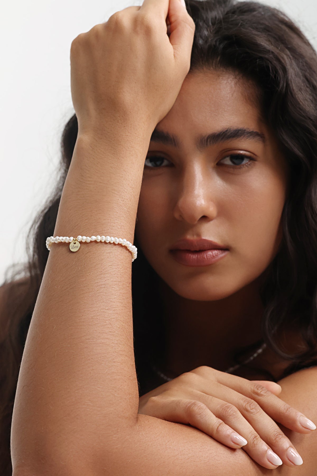 Frau trägt Süßwasserperlen Armband mit goldenem Anhänger, Modelaufnahme mit erhobenem Arm