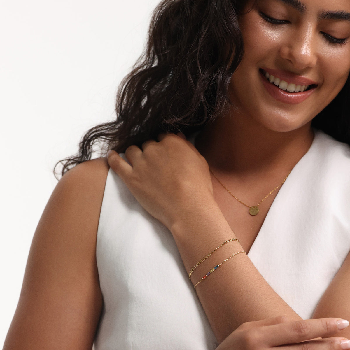 Frau trägt personalisiertes Geburtsstein-Armband in Gold am Handgelenk neben passender Kette