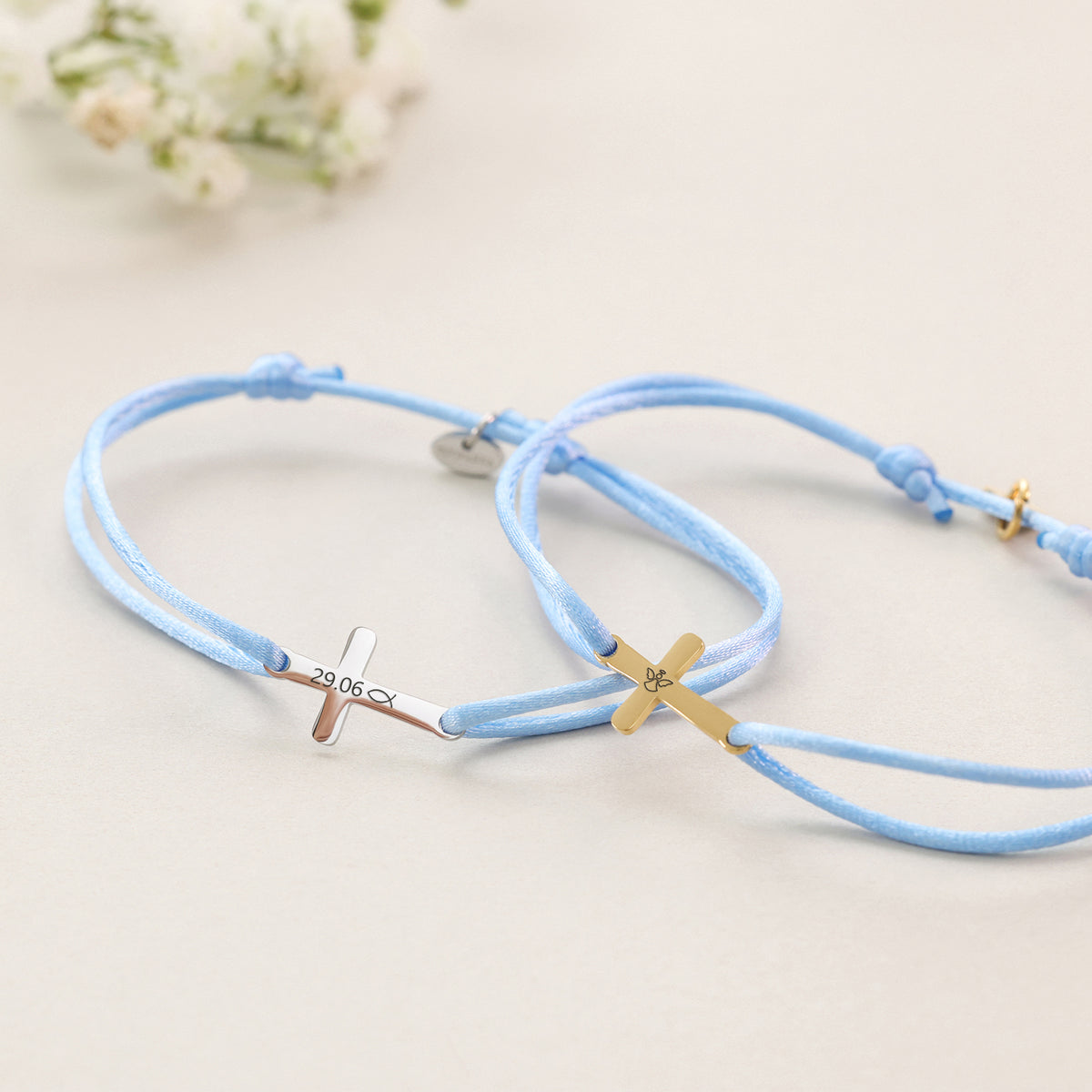 Detailansicht zweier Satinarmbänder mit graviertem Kreuz-Anhänger in Silber und Gold