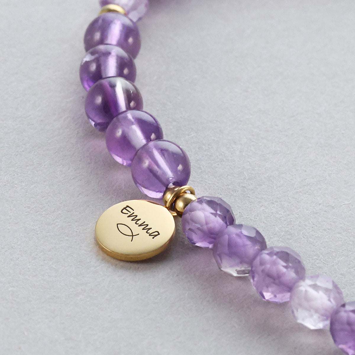 Nahaufnahme des Amethyst-Armbands mit Gravurplättchen und Ichthys-Symbol