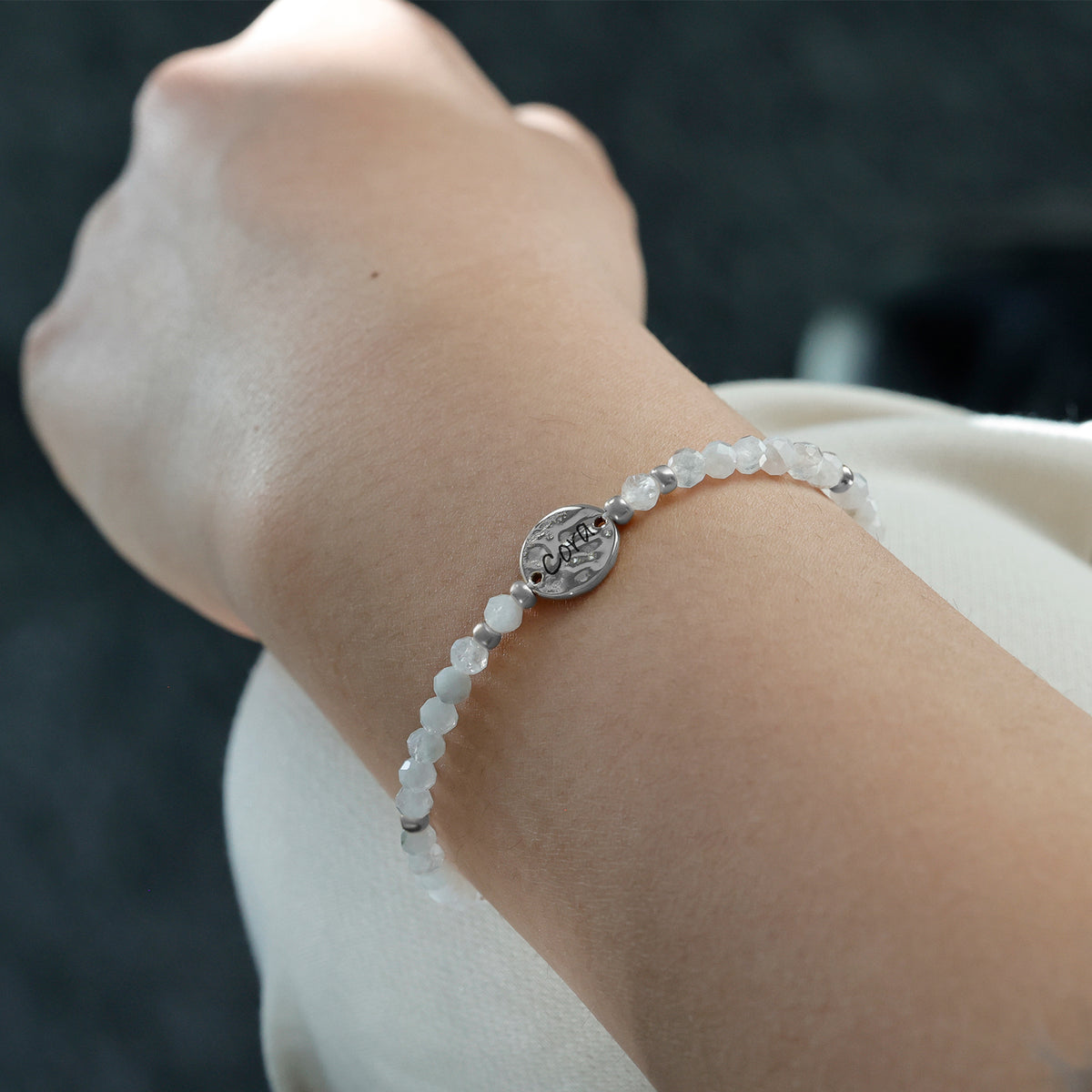 Frau trägt Mondstein Armband mit Hammerschlag Plättchen in Silber am Handgelenk