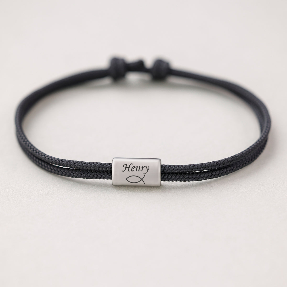 Segeltau Armband mit Gravur in Schwarz, einzelnes Plättchen mit Namen und Fisch-Symbol graviert