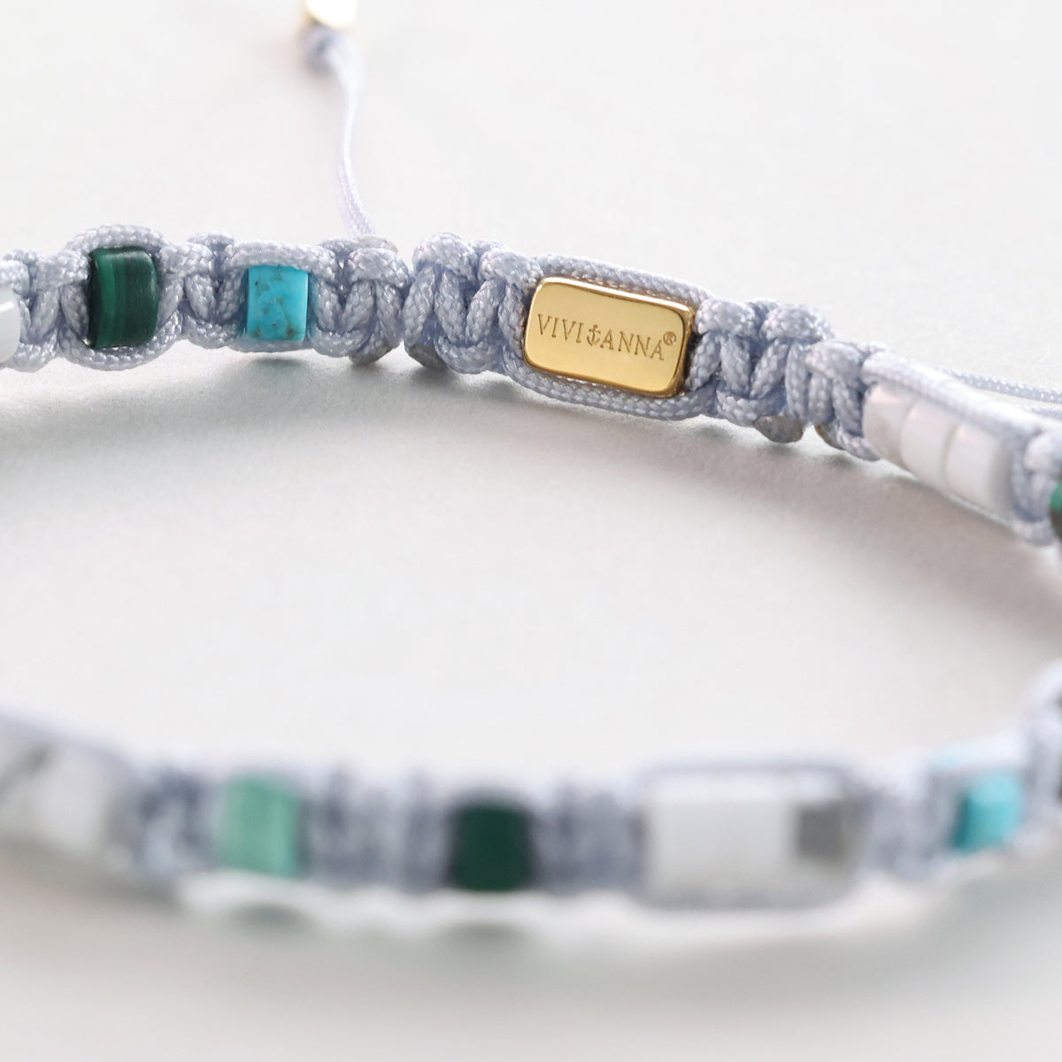 Detailansicht der VIVI&ANNA Plakette zwischen Türkis- und Malachit-Perlen am Armband