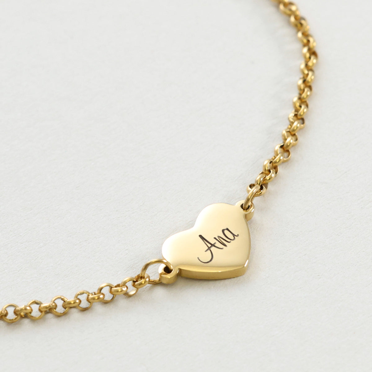 Nahaufnahme des goldenen Herz-Plättchens mit Gravur 'Ana' am Armband