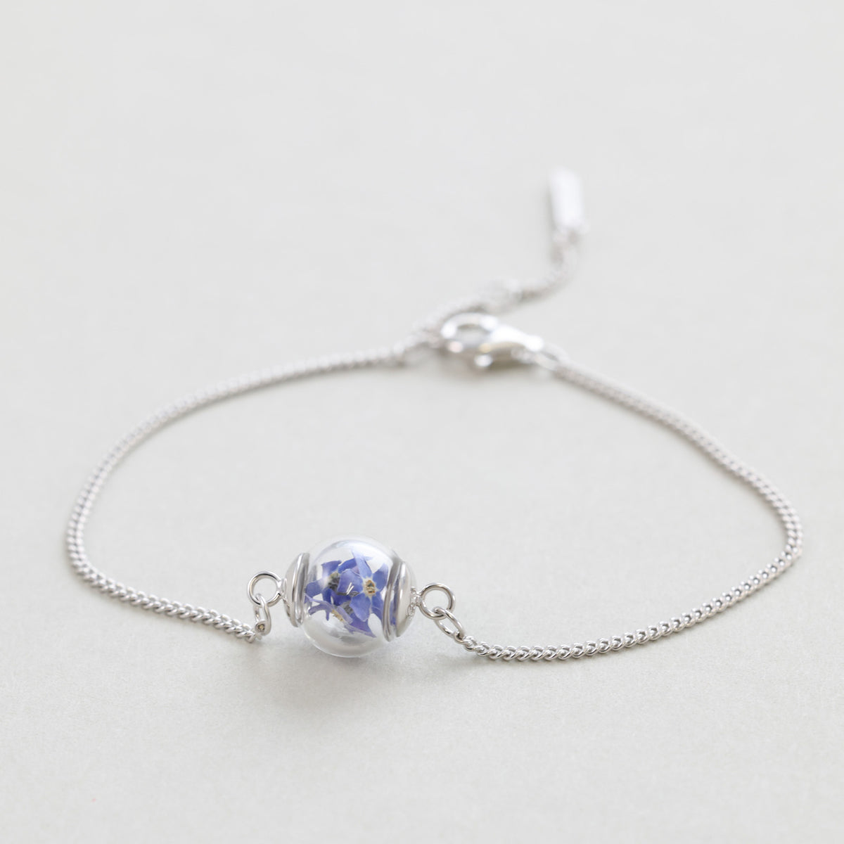 Vergissmeinnicht-Armband mit Gravur in Silber, liegend auf hellem Untergrund