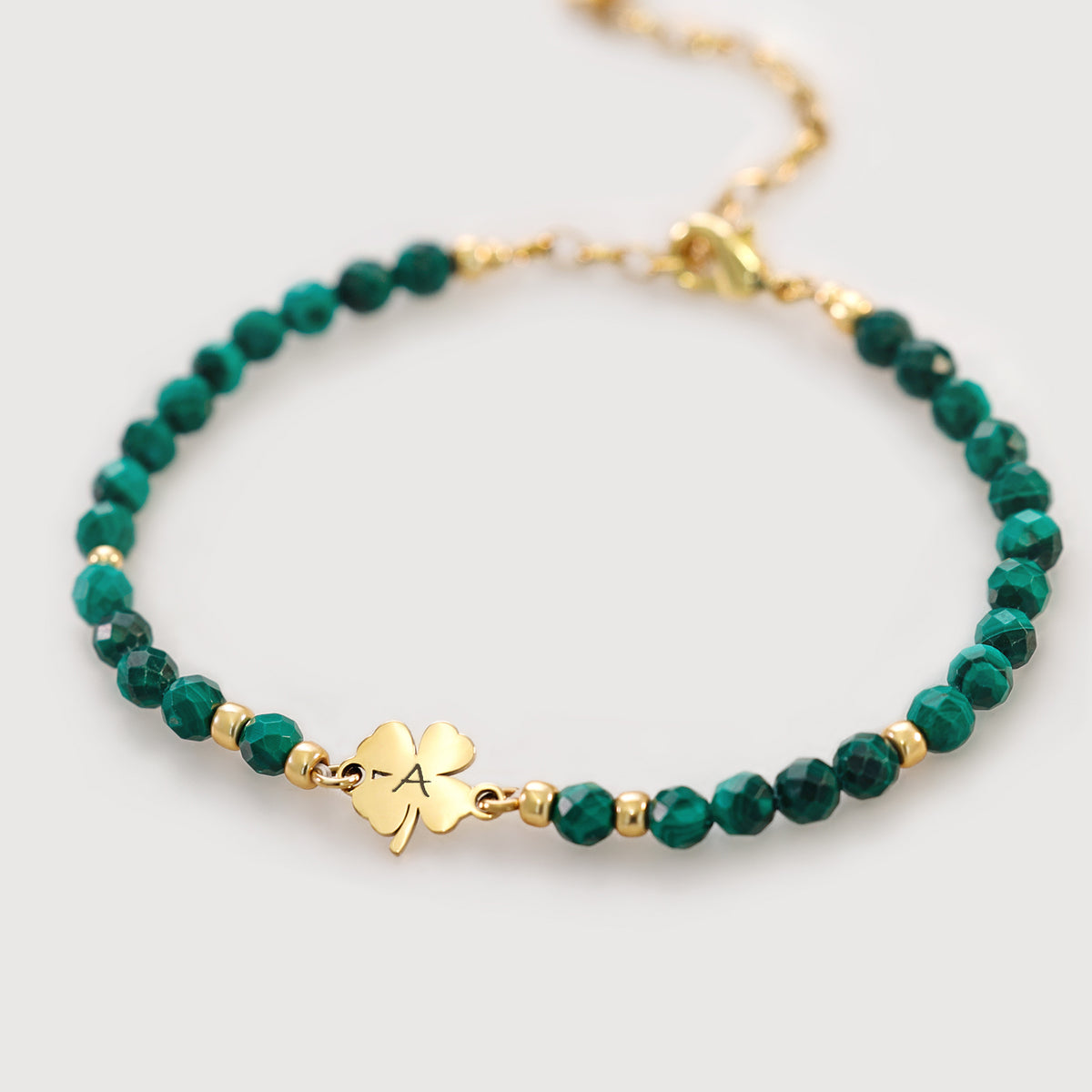 Malachit-Armband mit Kleeblatt in Gold – Perlenarmband mit graviertem Kleeblattanhänger freigestellt