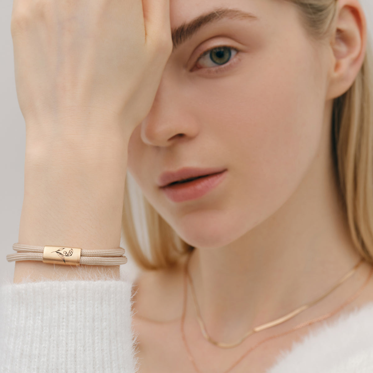 Geburtsblumen Armband aus Segeltau mit Wunschgravur in Beige – Frau trägt Armband mit Blumengravur am Handgelenk