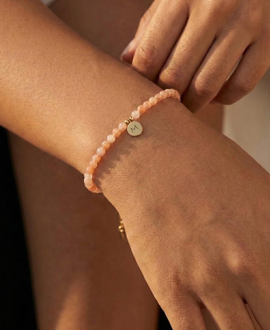 Frau trägt Sonnenstein-Armband mit graviertem Anhänger am sonnenbeschienenen Handgelenk