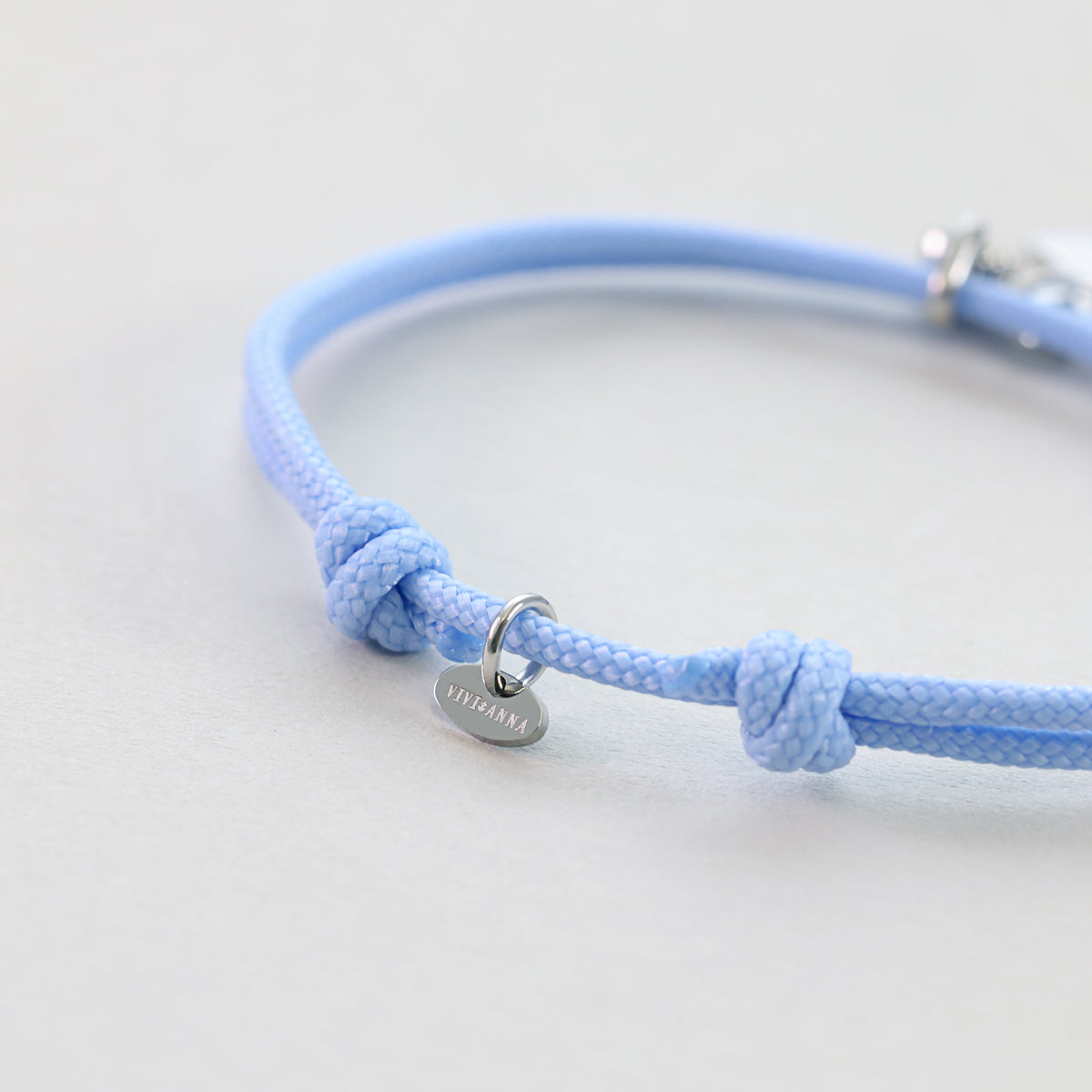 Nahaufnahme des Knotens und der Silberplakette am hellblauen Segeltau Armband