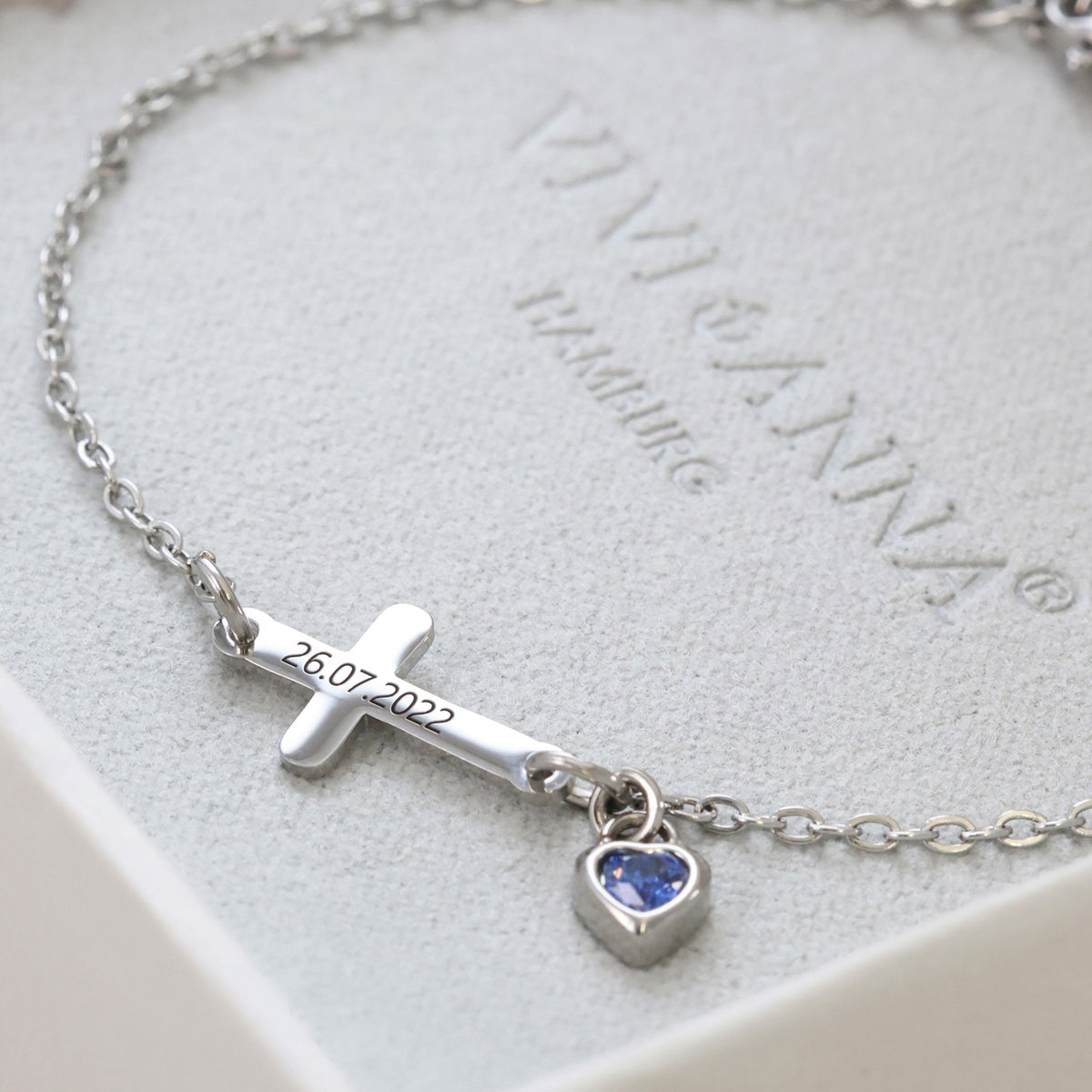 Kreuzarmband mit Herz-Geburtsstein – silbernes Armband graviert mit Datum, auf Geschenkbox drapiert