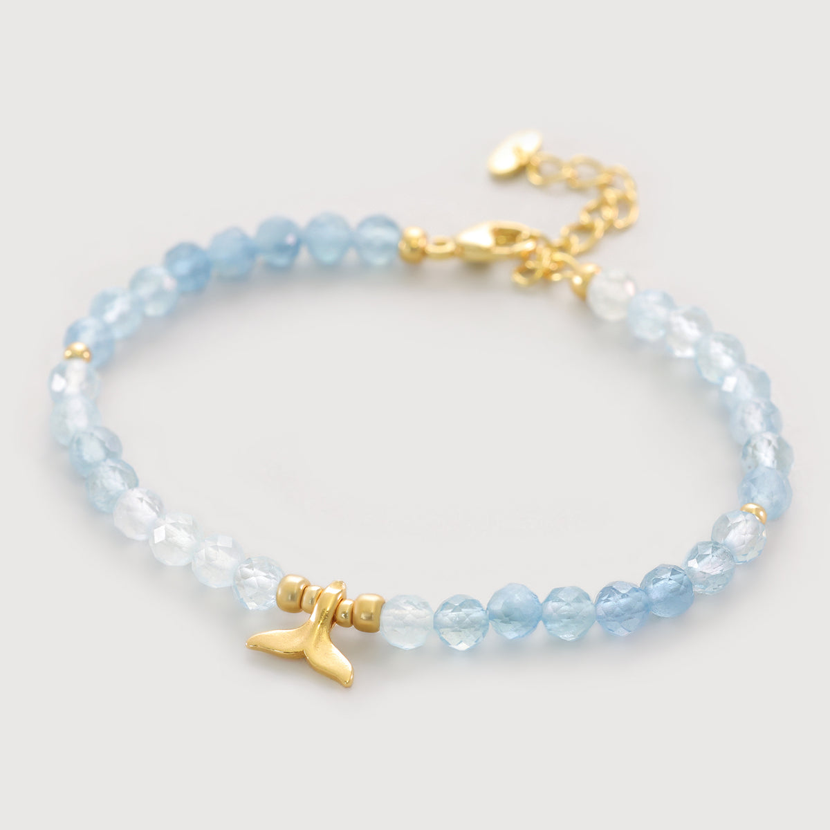 Aquamarin Armband mit Walflosse Anhänger in Gold, freigestellt auf hellem Hintergrund