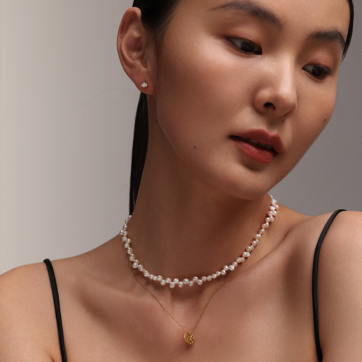 Frau trägt Süßwasserperlenkette in Spitzenoptik als Choker, kombiniert mit Goldkette und Anhänger