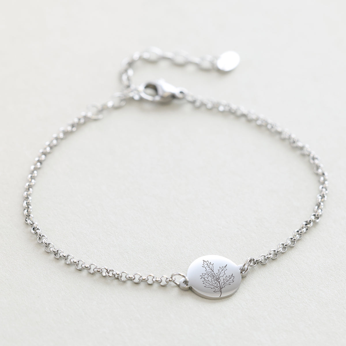 Geburtsblumen-Armband mit rundem Plättchen in Silber, flach liegend mit floraler Gravur