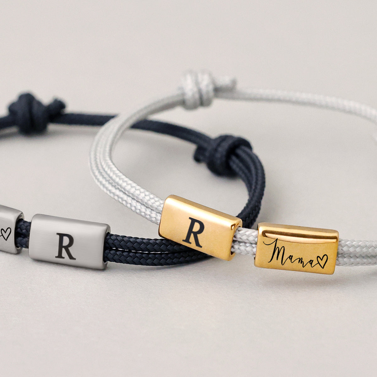Zwei Segeltau Armbänder mit Gravurperlen – navy mit Initiale 'R' und Herz, weiß mit 'R' und 'Mama'