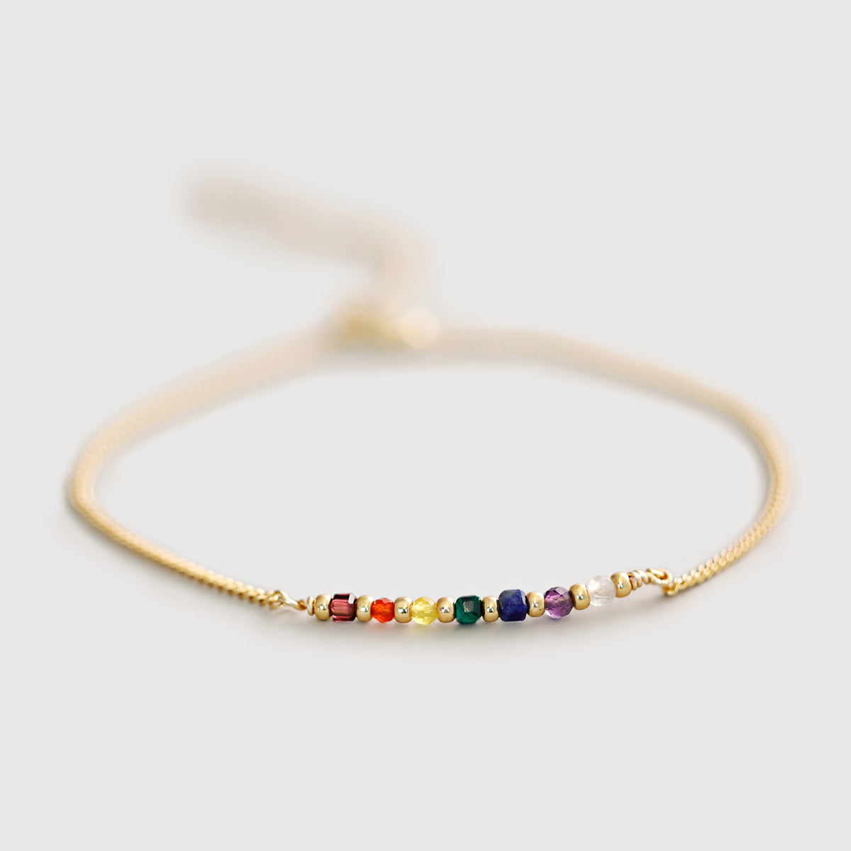 Chakra Armband in Gold mit bunten Edelstein-Perlen auf hellem Untergrund