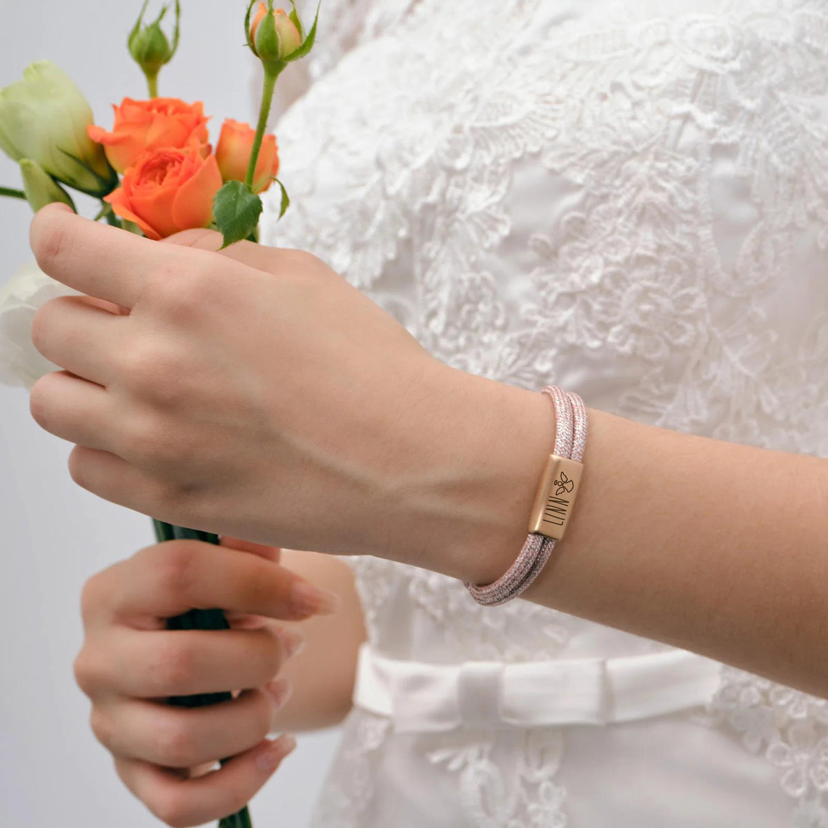 Glitzerndes Segeltau-Armband mit persönlicher Gravur – Mädchen trägt Armband mit Gravur beim Blumenhalten