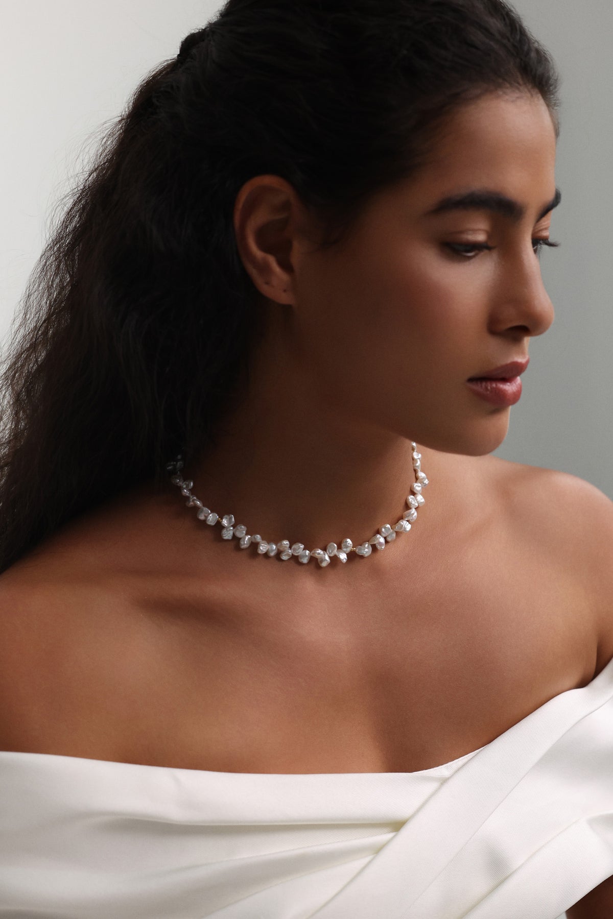 Frau trägt Barockperlen-Kette in Naturform zu schulterfreiem Look