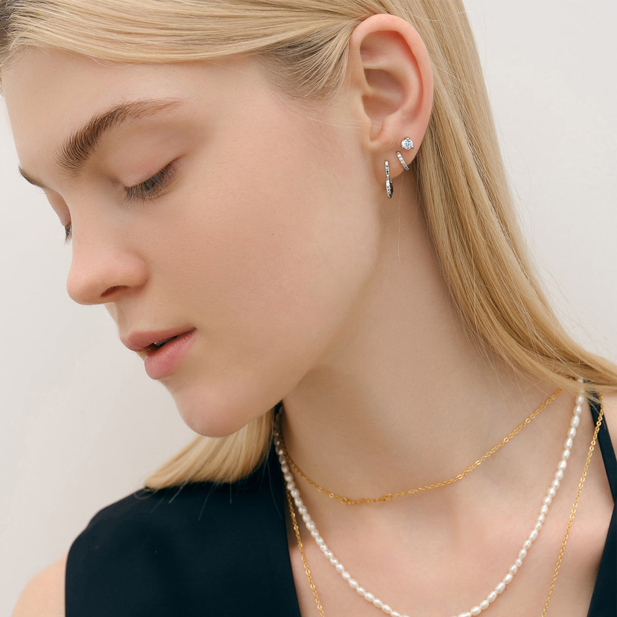 Frau trägt Ohrstecker mit Zirkonia aus 925er Sterling Silber in Silber mit Perlen- und Goldkette