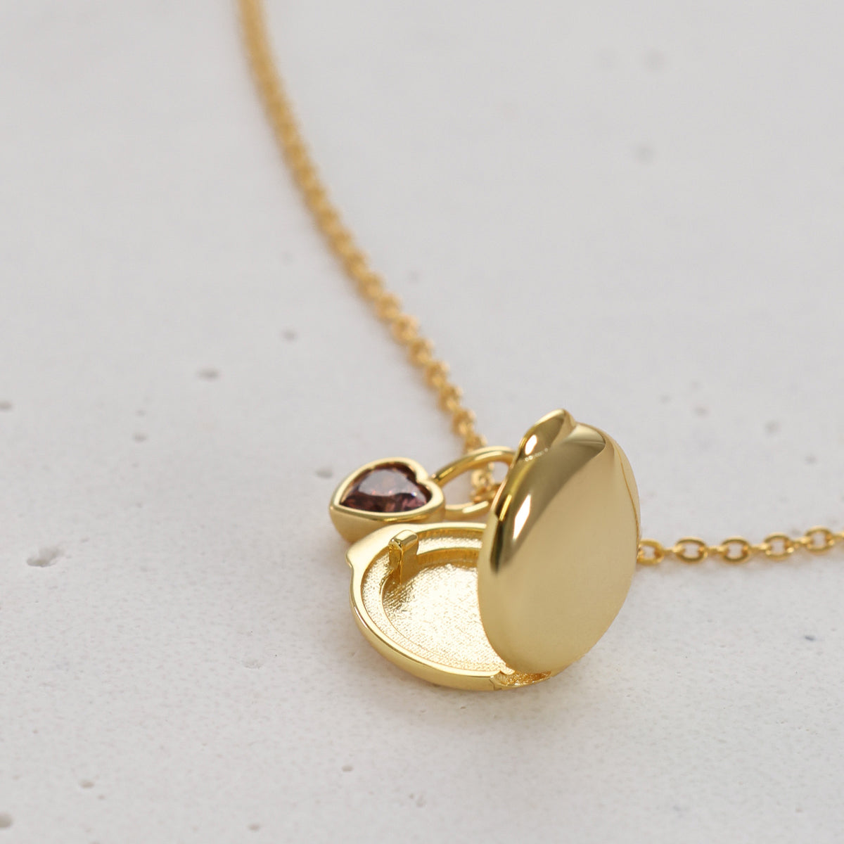 Geöffnetes Mini Medaillon in Gold mit rosa Herz-Geburtsstein, Nahaufnahme