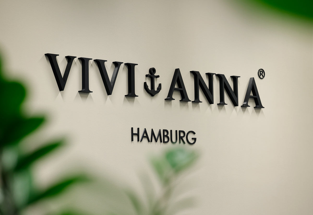 Schriftzug 'VIVIANNA Hamburg' an der Atelierwand, davor grüne Blätter unscharf