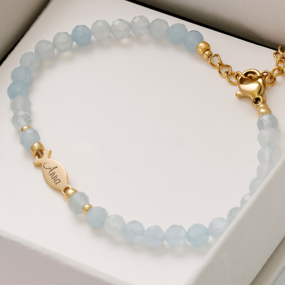 Aquamarin Ichthys Armband auf Geschenkbox, Fisch-Anhänger graviert mit dem Namen „Anna“