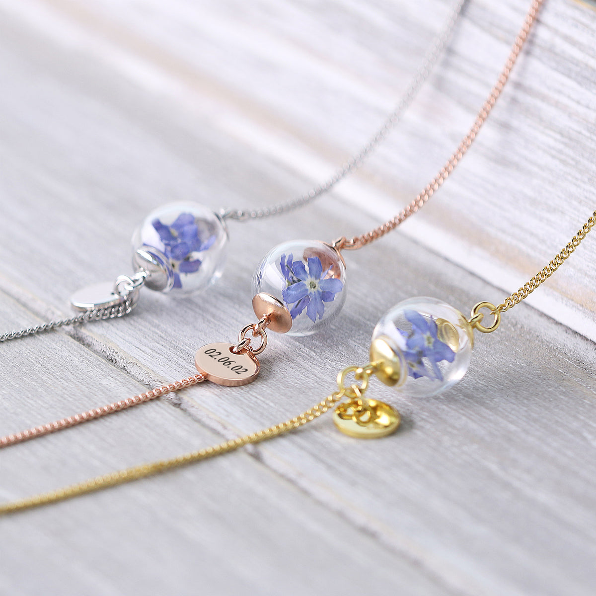 Drei Vergissmeinnicht-Armbänder mit Gravur in Silber, Roségold und Gold nebeneinander