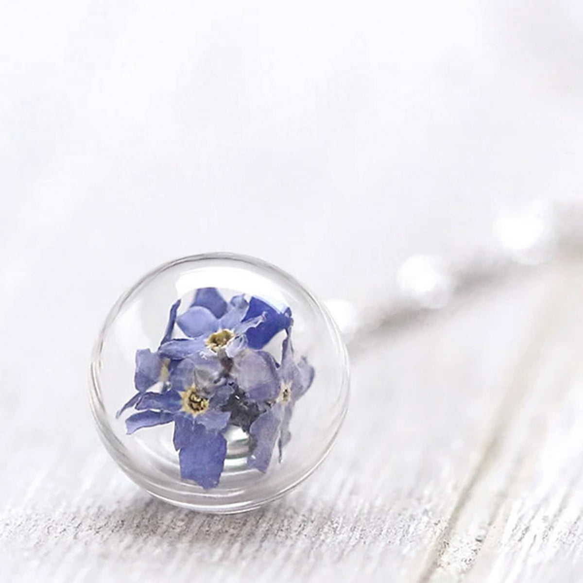 Nahaufnahme der Glaskugel mit echten blauen Vergissmeinnicht-Blüten