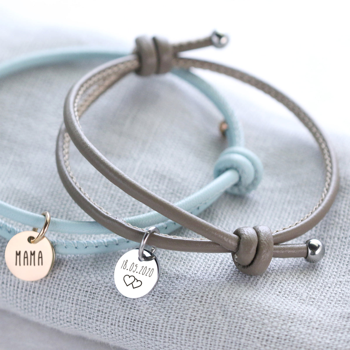 Personalisiertes Lederarmband mit Gravurplättchen – hellblaues Armband 'Mama' und graues Armband mit Datum und Herzen