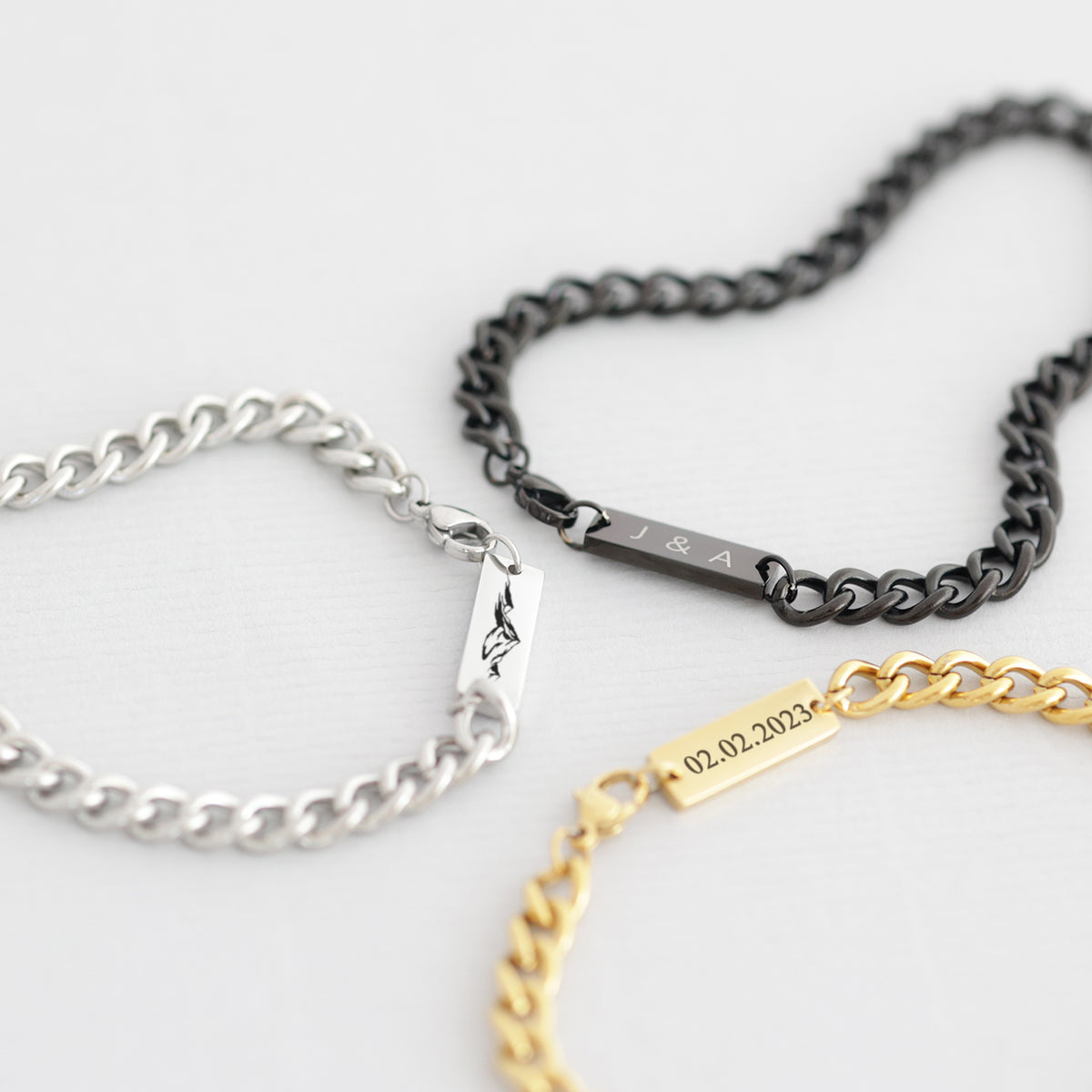 Drei Panzerarmbänder mit Gravurplättchen in Silber, Schwarz und Gold mit unterschiedlichen Motiven