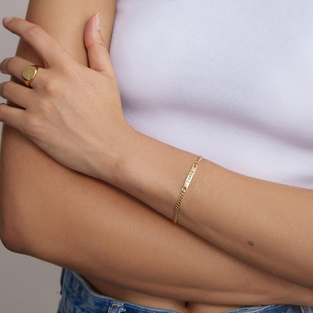 Frau trägt goldenes personalisiertes Armband am Handgelenk, Nahaufnahme mit Ring