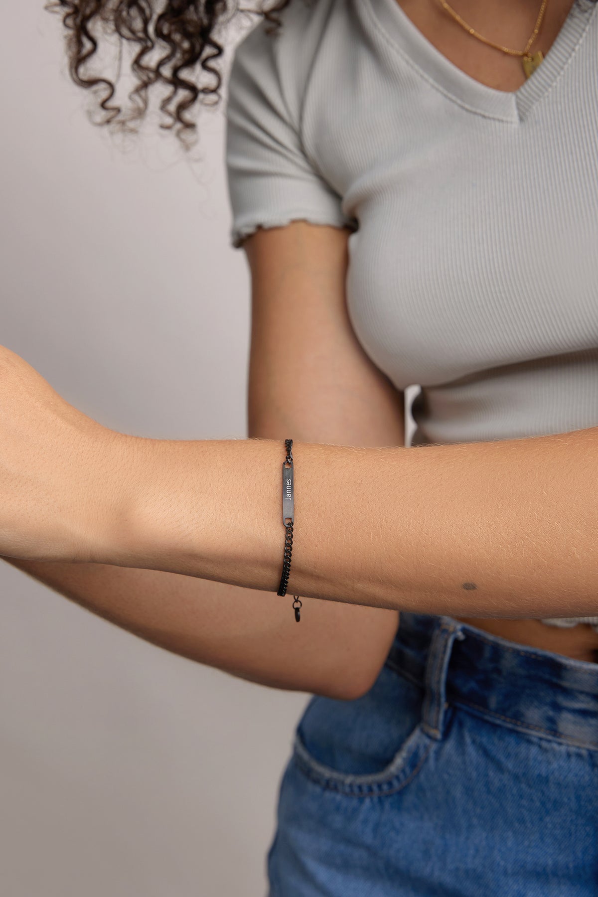 Frau trägt schwarzes personalisiertes Armband mit dem Namen 'Jannes', Nahaufnahme am Arm